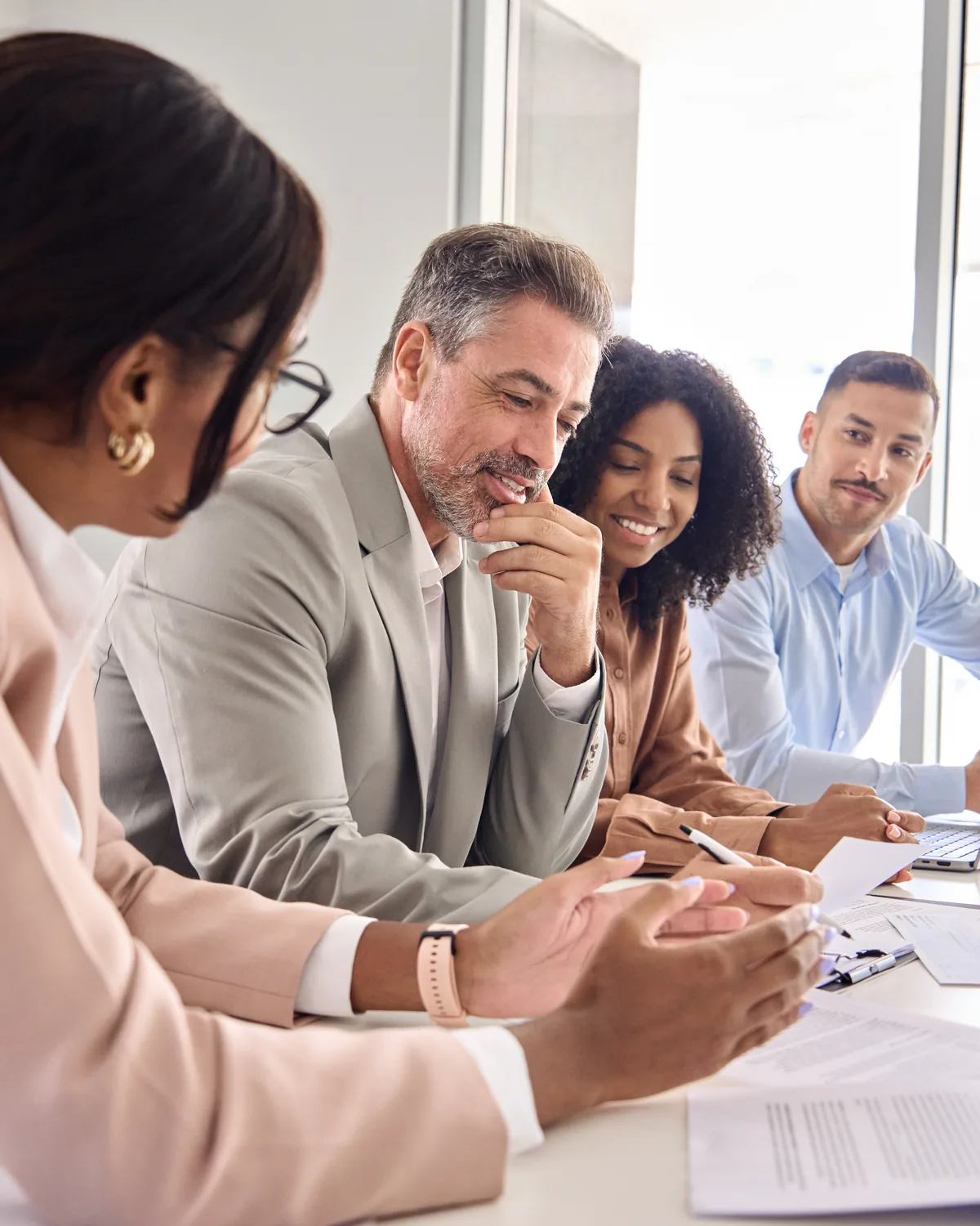 A diverse team in discussion around documents in a meeting room.
