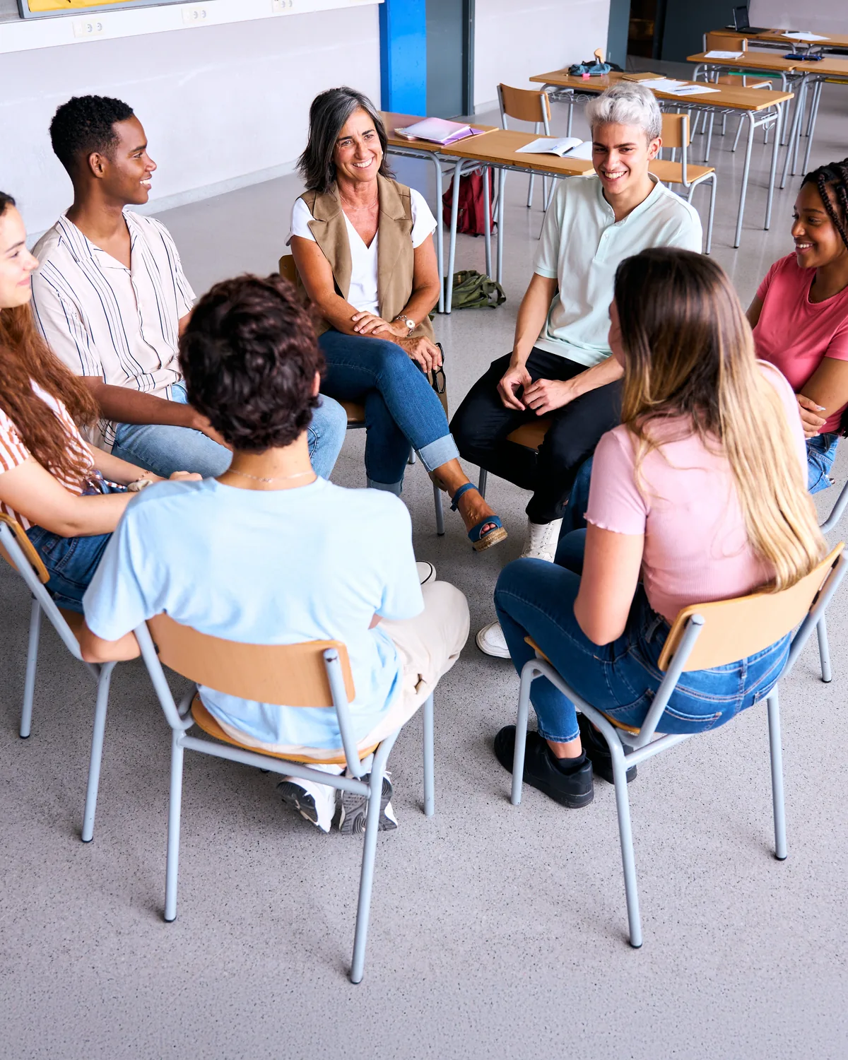 Students and a teacher seated in a circle in a classroom.