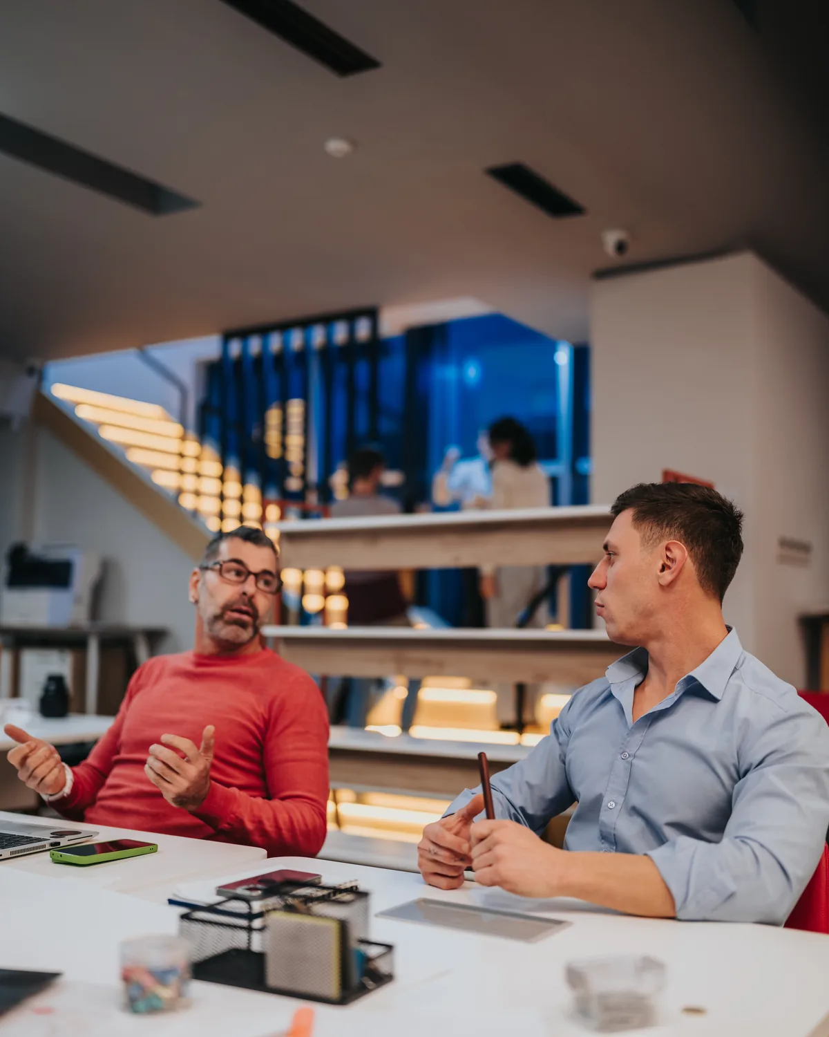 Two colleagues in conversation across an office table.